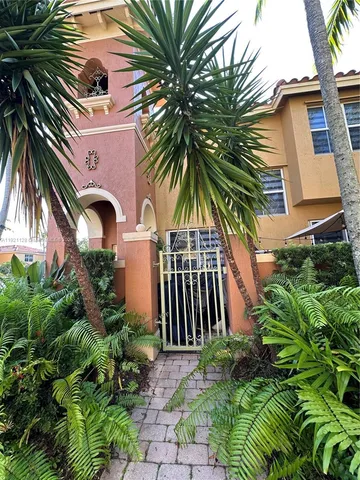 a front view of multi story residential apartment building with yard and entryway