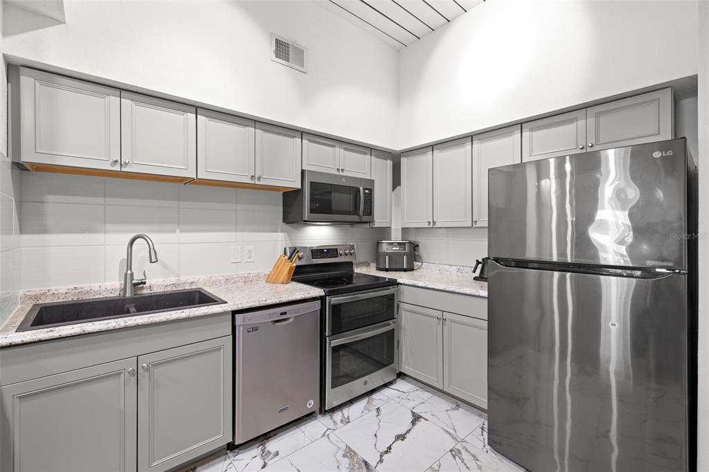 2410 West Azeele Street, Unit 214 Tampa, FL 33609 - Photo 5 of 24 a kitchen with a sink a refrigerator a microwave and cabinets