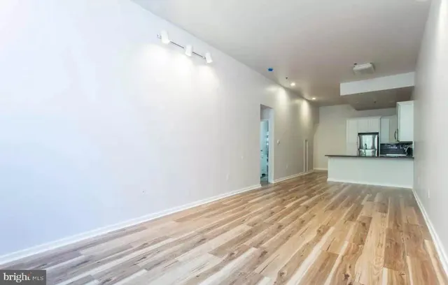 a view of a big room with wooden floor and a kitchen