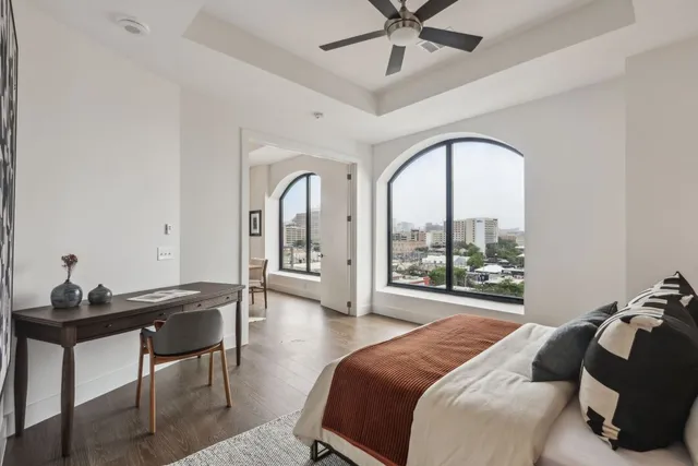 a bedroom with a bed a desk and chair with wooden floor
