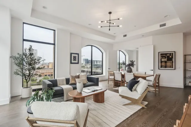 a living room with furniture large window and wooden floor