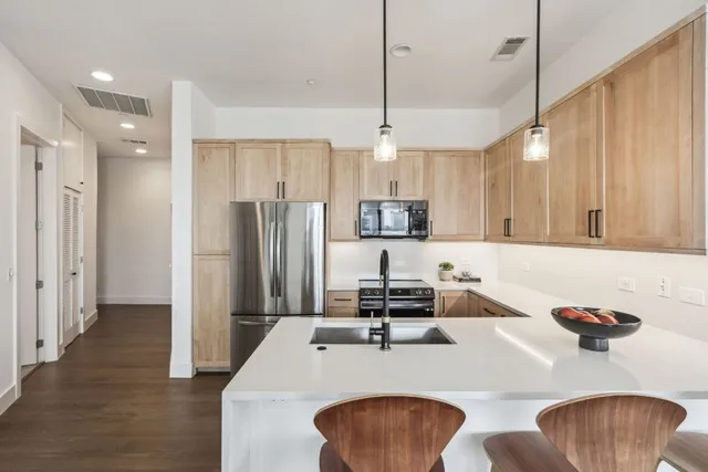 a kitchen with stainless steel appliances granite countertop a sink a stove a refrigerator a center island and chairs