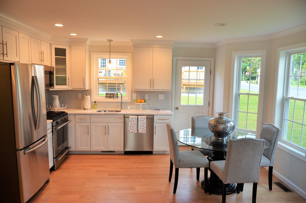 81 Riley Road, Unit 113 Tyngsborough, MA 01879 - Photo 5 of 14 a kitchen with stainless steel appliances granite countertop a stove a refrigerator a kitchen island a table and chairs