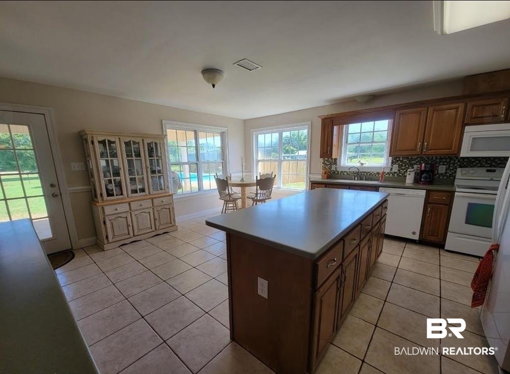 16311 Old Brady Road Bay Minette, AL 36507 - Photo 7 of 38 Kitchen featuring a central island with countertop, wood-finish cabinetry, tile flooring, and a patterned tile backsplash