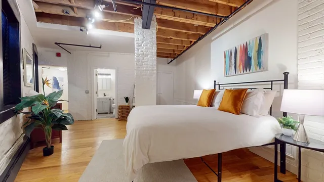 a bedroom with a large bed and a potted plant