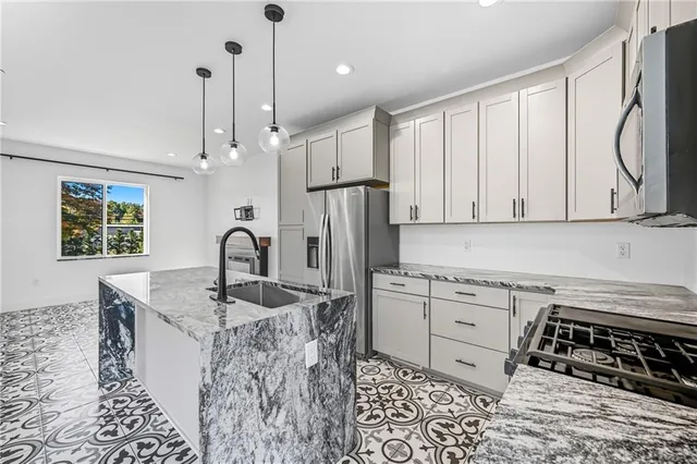 a kitchen with stainless steel appliances granite countertop a sink stove and refrigerator
