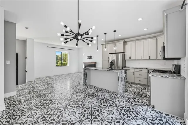 a kitchen with stainless steel appliances granite countertop a stove a sink a refrigerator a center island a stove and a window