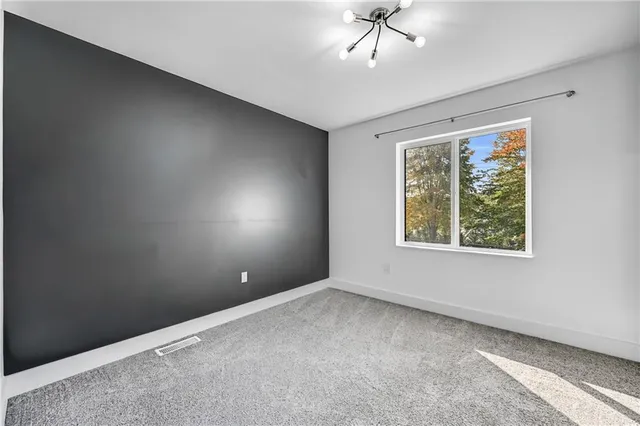 an empty room with windows and chandelier fan