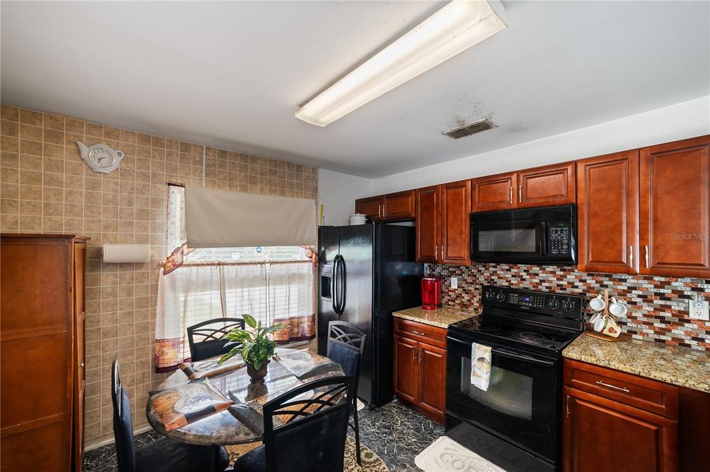 5624 Indialantic Drive Orlando, FL 32808 - Photo 9 of 17 a kitchen with granite countertop a stove and a refrigerator