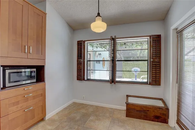 a view of an empty room with a window and kitchen view
