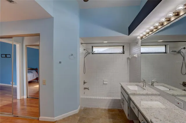 a bathroom with a granite countertop sink a mirror and shower