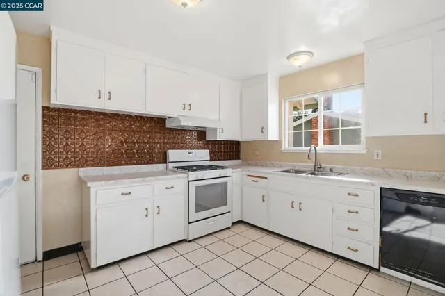 a kitchen with granite countertop white cabinets stainless steel appliances a sink and a window