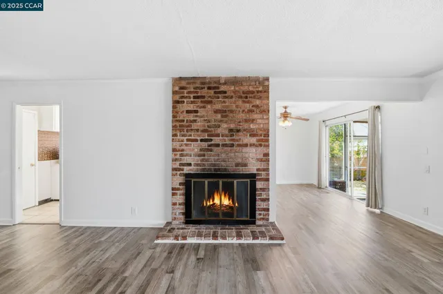 an empty room with wooden floor fireplace and window