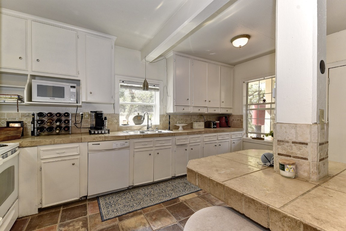 4525 Bell Springs Road Dripping Springs, TX 78620 - Photo 25 of 38 a white kitchen with granite countertop white cabinets sink and stove