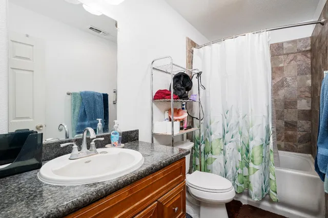 a bathroom with a granite countertop sink mirror vanity and toilet