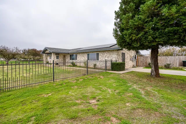 a view of a house with backyard and a tree