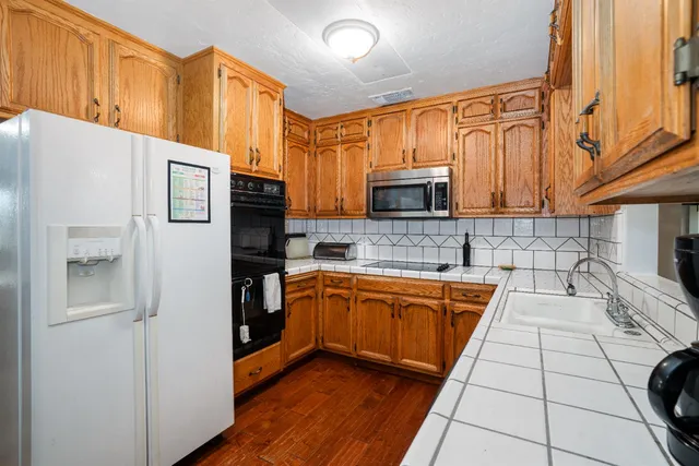 a kitchen with stainless steel appliances granite countertop a refrigerator a stove top oven and a sink