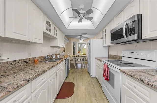 a kitchen with stainless steel appliances granite countertop a sink a stove and a wooden cabinets