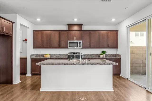 a kitchen with stainless steel appliances granite countertop a stove a sink dishwasher and a refrigerator with wooden floor