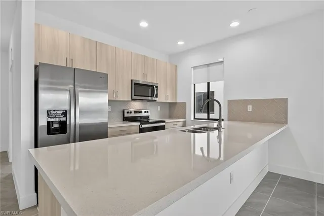 a kitchen with kitchen island a counter top space appliances and a sink