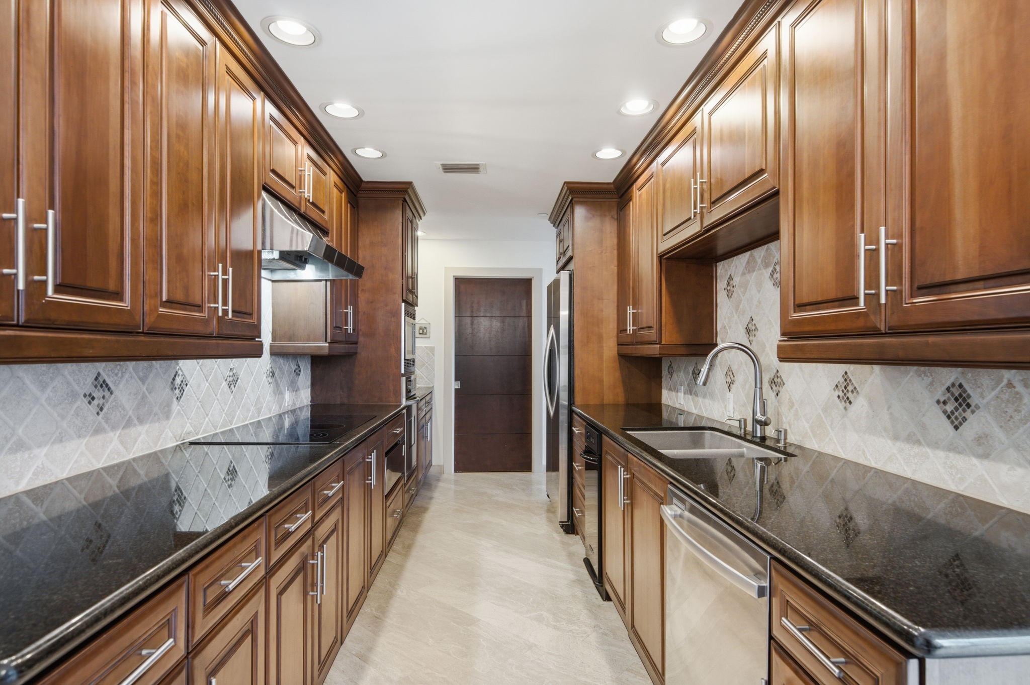 3350 McCue Road, Unit 2402 Houston, TX 77056 - Photo 2 of 49 Rich wood cabinetry pairs seamlessly with sleek black granite countertops in this upscale galley-style kitchen. High-end stainless steel appliances, a modern undermount sink, and extensive storage make this culinary space both stylish and practical for everyday living.