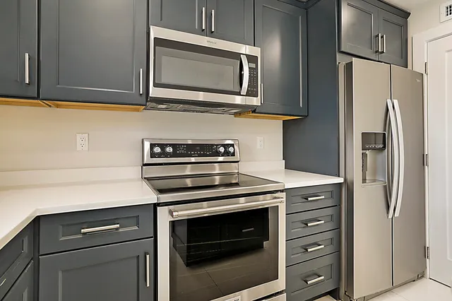 a kitchen with stainless steel appliances white cabinets and a stove a refrigerator with wooden cabinet