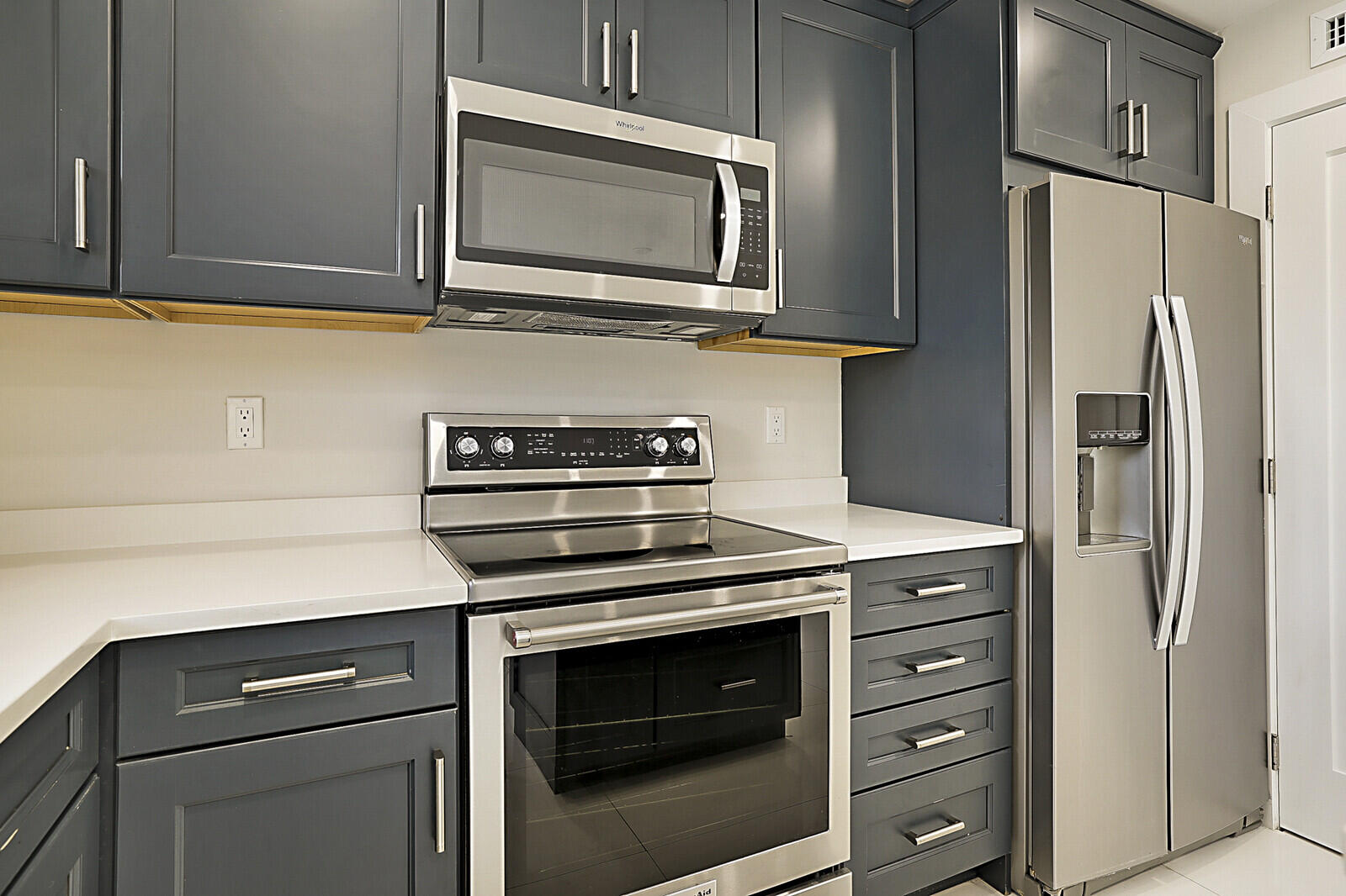 1439 South Ocean Boulevard, Unit 208 Lauderdale-by-the-Sea, FL 33062 - Photo 13 of 27 a kitchen with stainless steel appliances white cabinets and a stove a refrigerator with wooden cabinet
