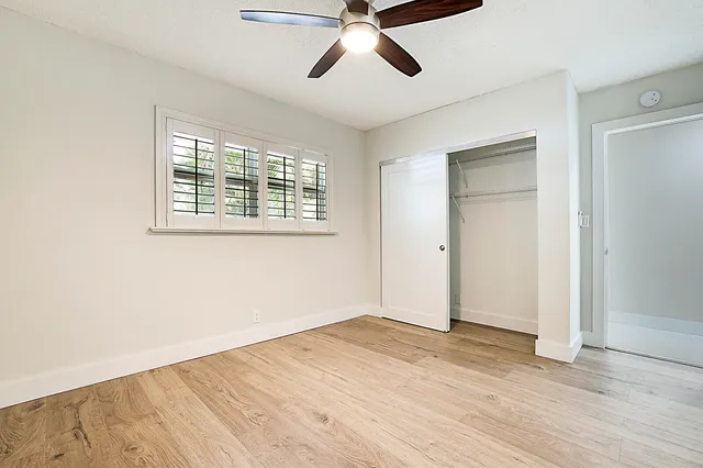 a view of empty room with wooden floor and fan