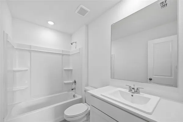 a bathroom with a bathtub shower sink vanity mirror and toilet