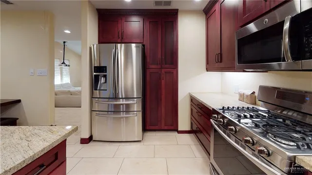 a kitchen with stainless steel appliances granite countertop a refrigerator and a stove top oven