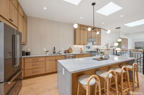 a kitchen with stainless steel appliances granite countertop a sink a stove a kitchen island with chairs and cabinets