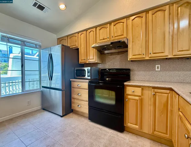a kitchen with granite countertop wooden cabinets and a stove top oven