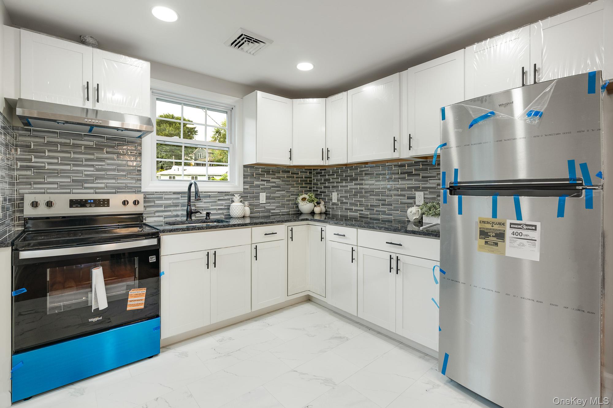 3167 Lincoln Drive Mohegan Lake, NY 10547 - Photo 11 of 34 a kitchen with stainless steel appliances granite countertop a refrigerator a sink dishwasher a stove and white countertops with wooden floor