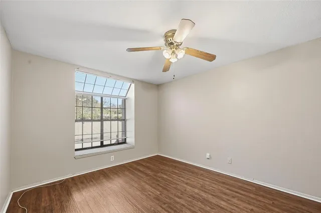 an empty room with wooden floor fan and windows