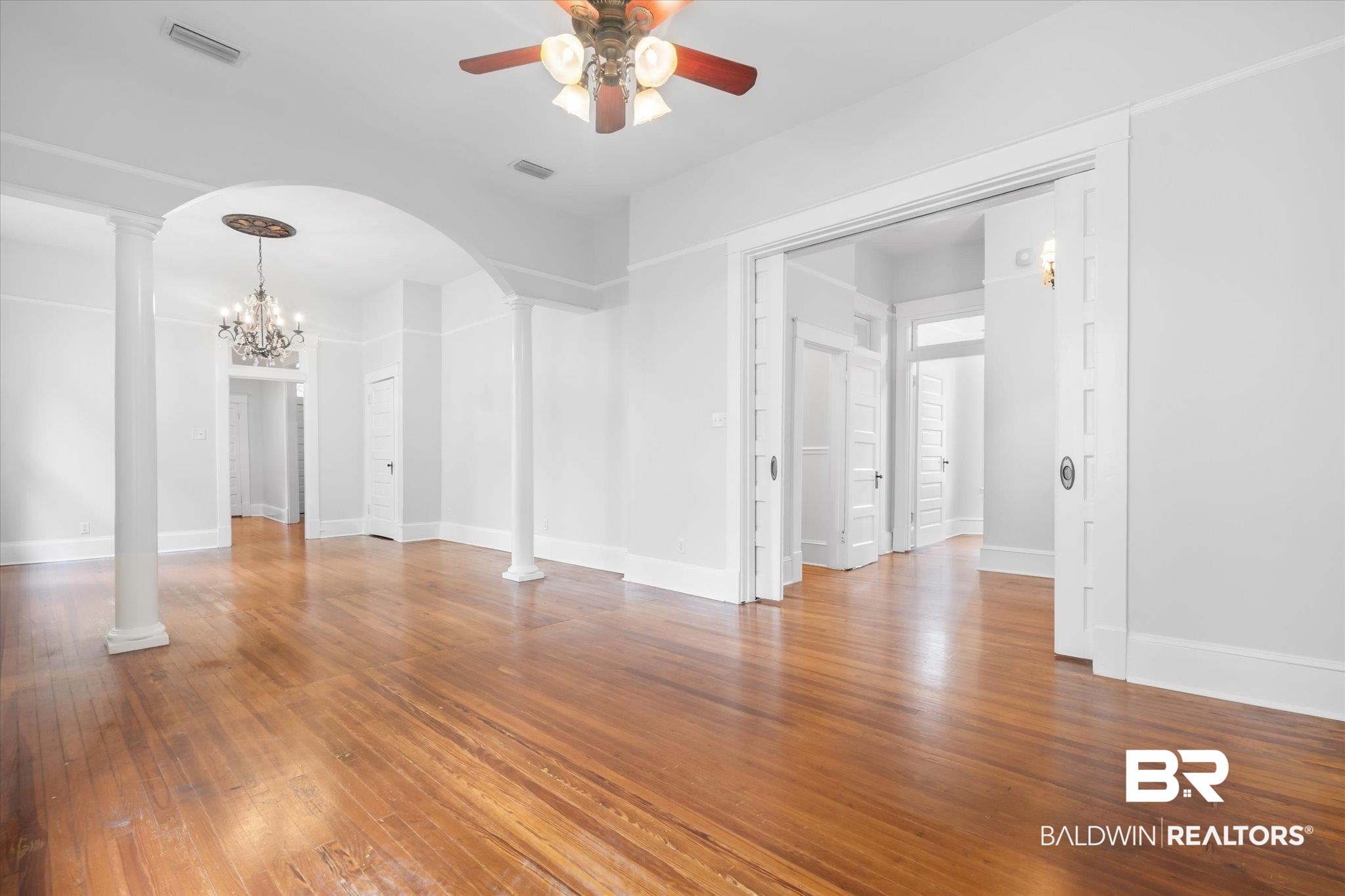 14 South Monterey Street Mobile, AL 36604 - Photo 5 of 41 Unfurnished room with wood-type flooring, ceiling fan with notable chandelier, and decorative columns
