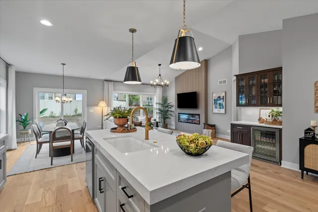 a kitchen with stainless steel appliances granite countertop a sink a stove and chairs with wooden floor