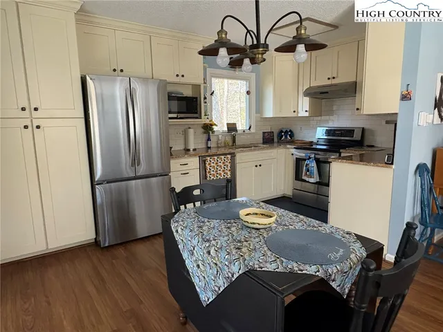 a kitchen with stainless steel appliances granite countertop a sink dishwasher a refrigerator a stove a microwave oven with a dining table and chairs