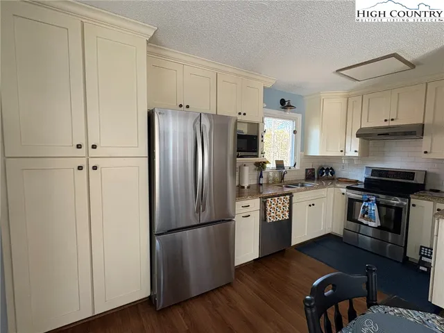 a kitchen with granite countertop stainless steel appliances a refrigerator a stove a sink and a microwave