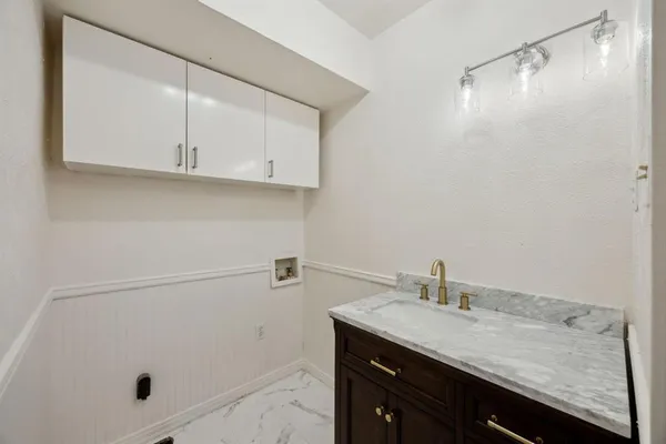 a bathroom with a granite countertop sink and white cabinets