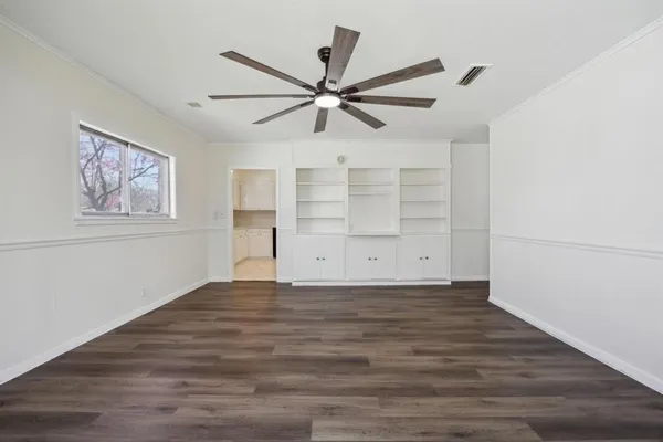 a view of a big room with wooden floor and windows