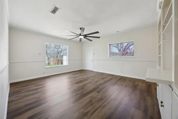 a view of empty room with wooden floor and fan