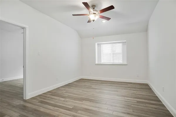 an empty room with wooden floor chandelier fan and windows