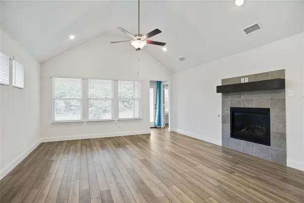 a view of an empty room with wooden floor fireplace and a window
