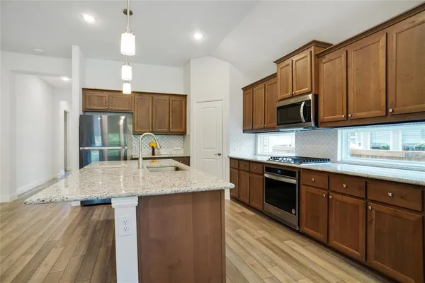 a kitchen with kitchen island stainless steel appliances a sink and cabinets