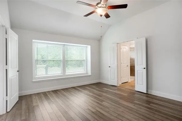 an empty room with wooden floor and a kitchen