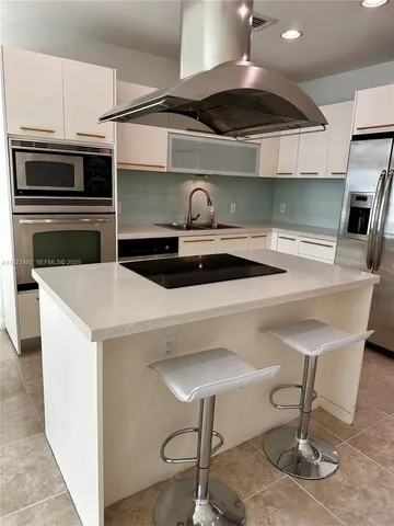 a kitchen with stainless steel appliances kitchen island a table chairs in it and wooden floors