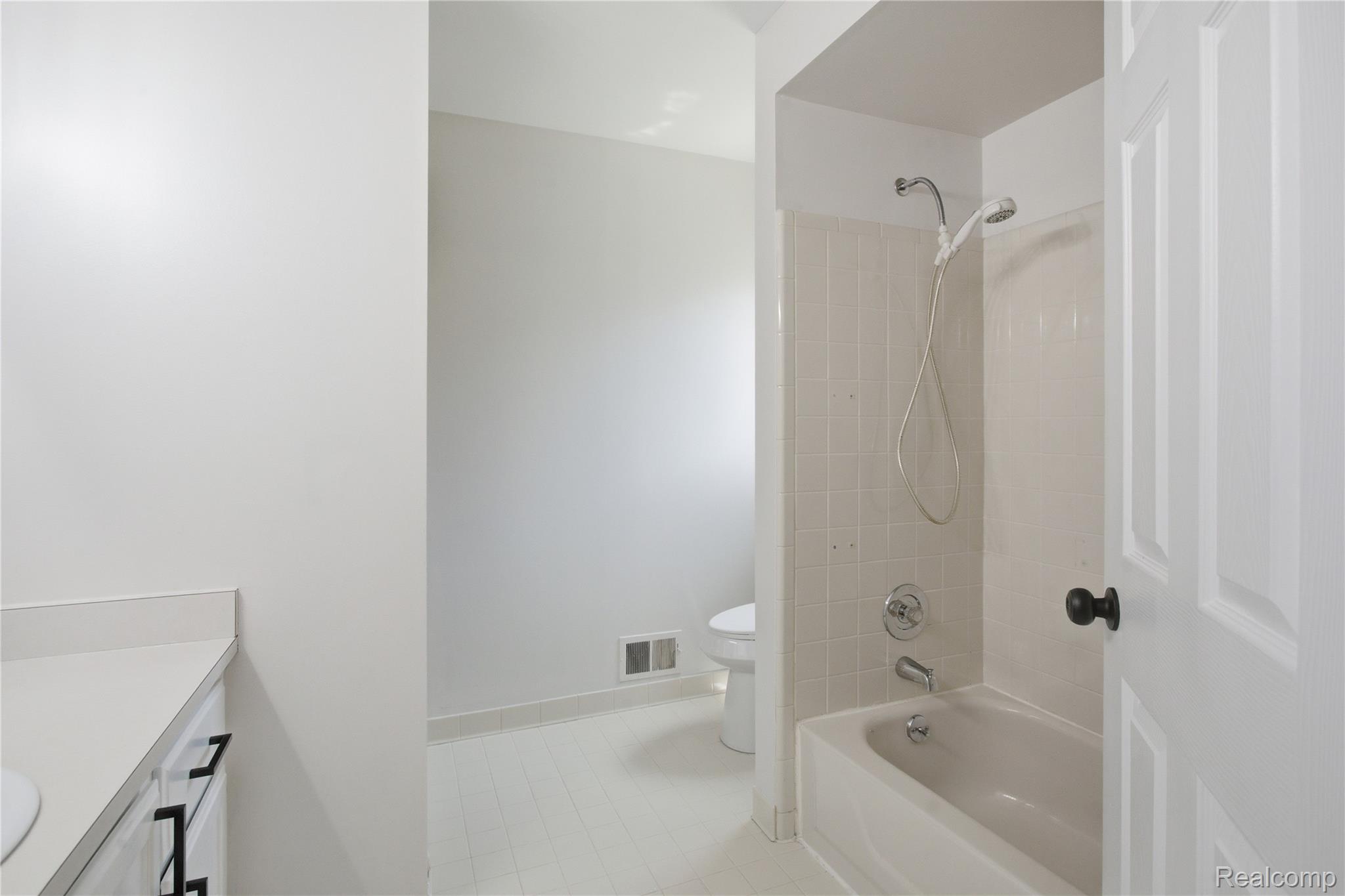 52658 Stag Ridge Drive Macomb, MI 48042 - Photo 22 of 28 White bathroom featuring a built-in tub with tile surround, white vanity with countertop, and black hardware