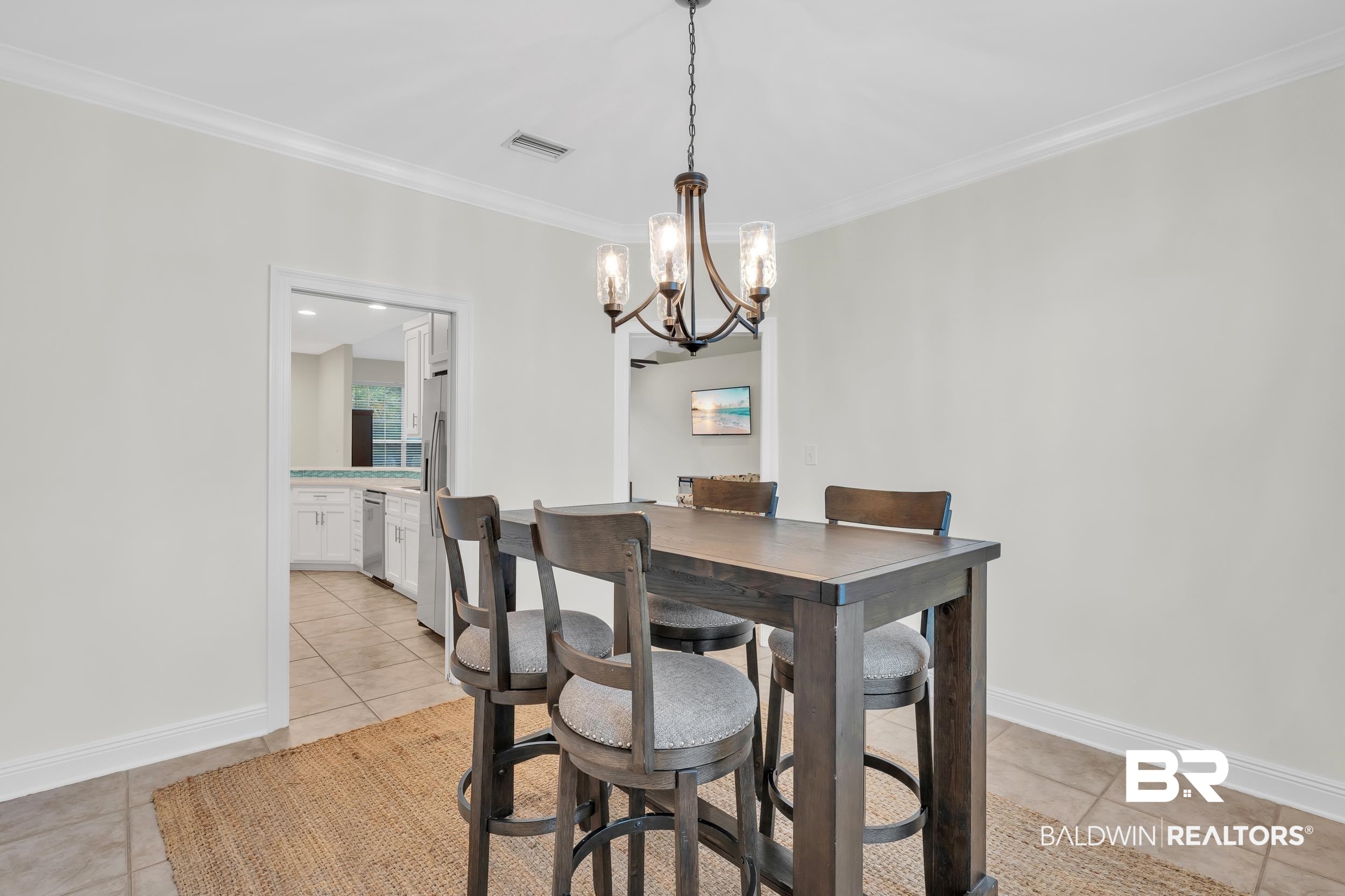 4606 Osprey Drive Orange Beach, AL 36561 - Photo 19 of 44 Dining room with a chandelier, crown molding, and light tile patterned floors