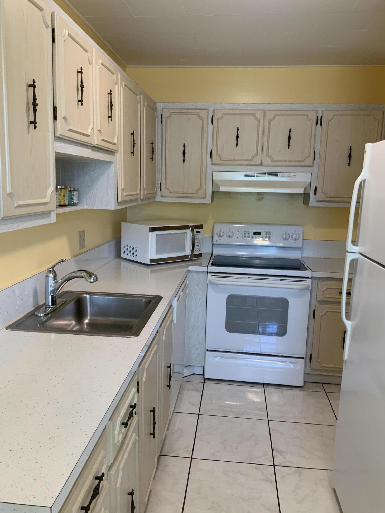 1121 Cactus Terrace, Unit 202 Delray Beach, FL 33445 - Photo 20 of 31 a kitchen with cabinets appliances and a sink