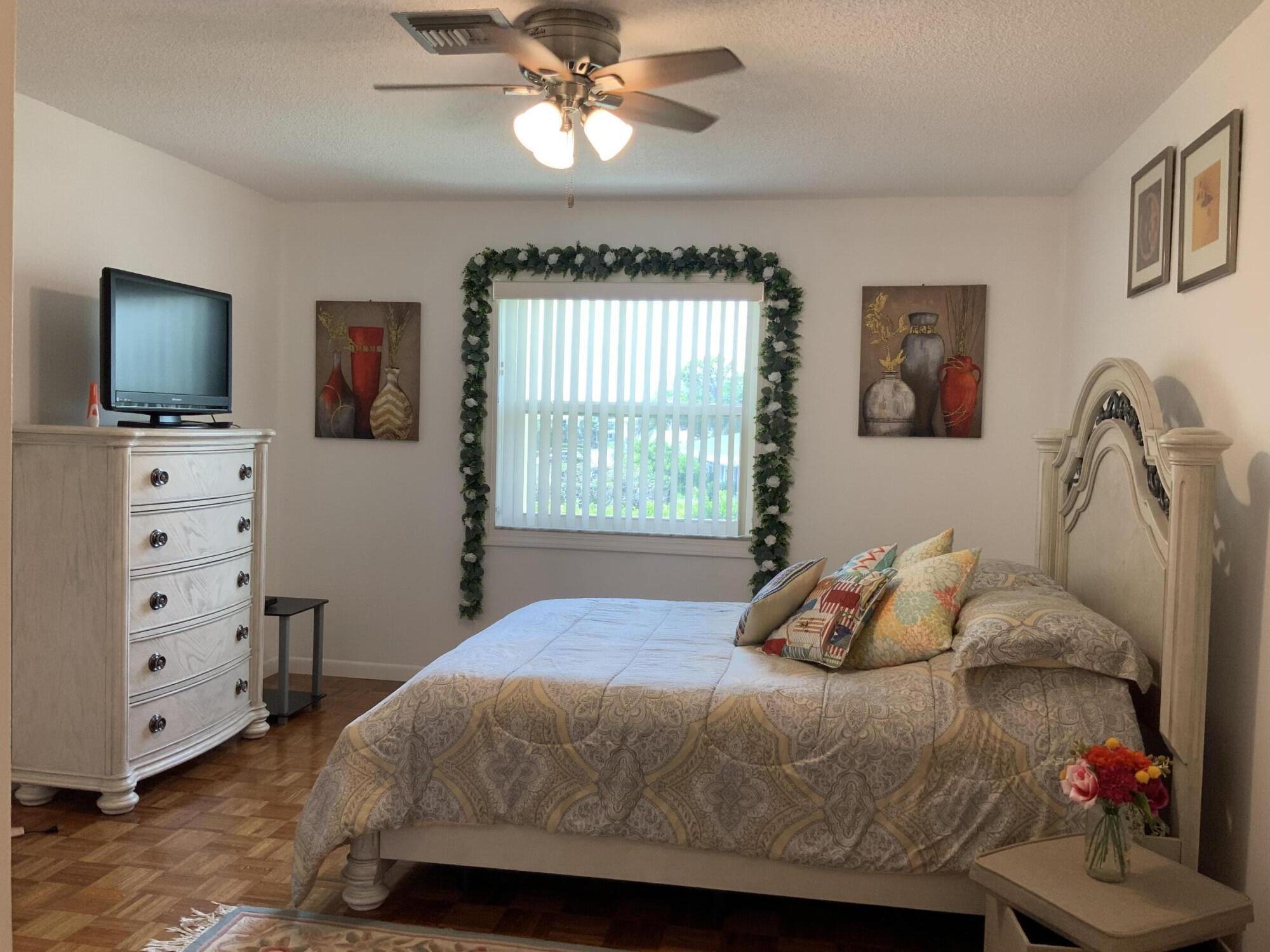 1121 Cactus Terrace, Unit 202 Delray Beach, FL 33445 - Photo 24 of 31 a bedroom with a bed and a flat screen tv